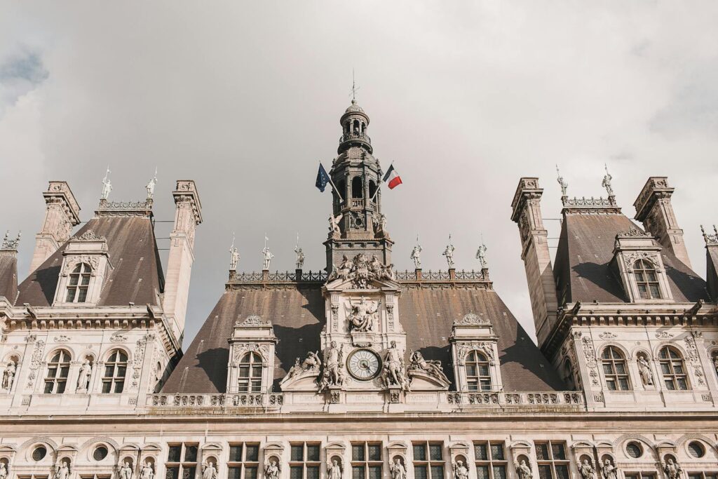 Stunning architectural detail of the iconic Hôtel de Ville in Paris with French flags.
